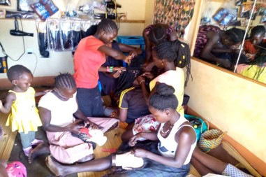 Girls learning hairdressing skills at community business point